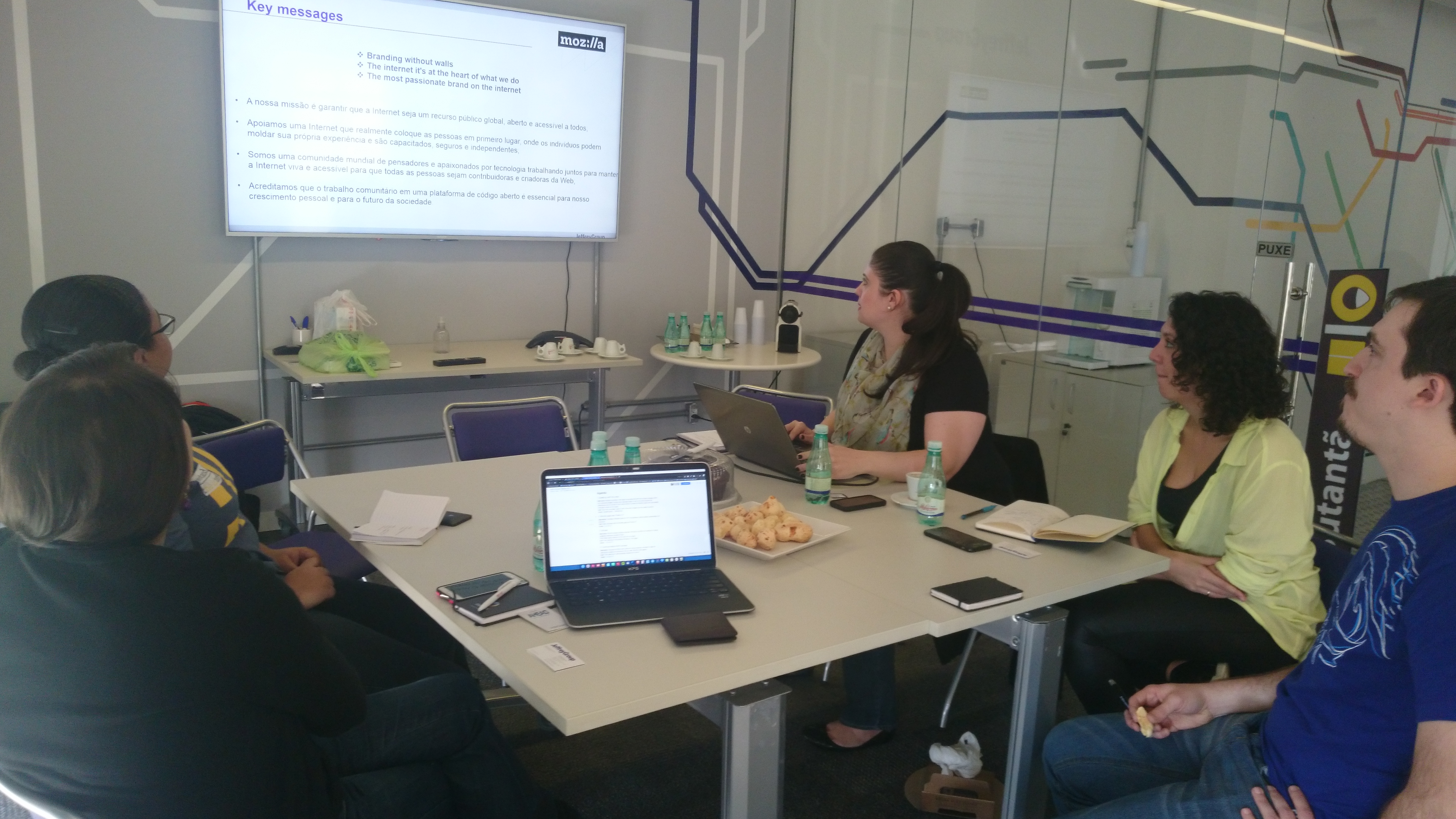 Image of people sitting at table, looking at a presentation screen